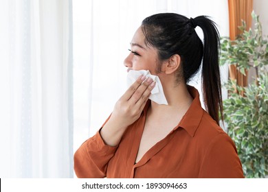 Young Happy Obese Woman Is Cleaning Her Face Using A Tissue Paper. Attractive Fat Woman Cleaning Her Face From Sweat With A Face Wipe By The Window At Home. 