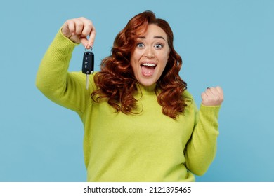 Young happy overjoyed chubby overweight plus size big fat fit woman wear green sweater hold car keys fob keyless system do winner gesture isolated on plain blue background People lifestyle concept.