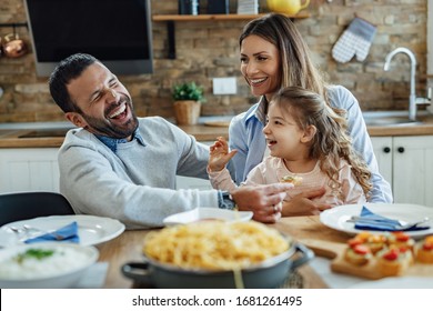 Young happy parents having fun with their small daughter during lunch at dining table.  - Powered by Shutterstock