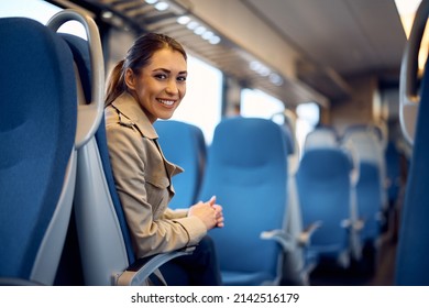 Young happy passenger enjoying on her journey by train and looking at camera. Copy space. 