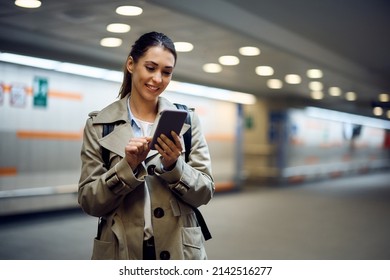 Young happy passenger text messaging on her cell phone at subway station. Copy space.  - Powered by Shutterstock