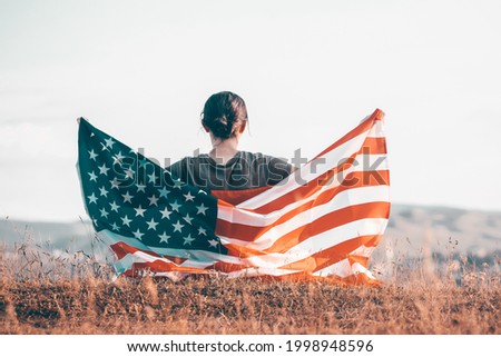 Young happy patriot girl holding the american flag on the 4th of July. 