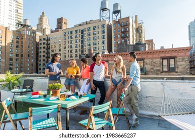 Young happy people having a barbecue dinner on a rooftop in New York - Group of friends having party and having fun