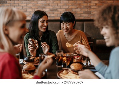 Young happy people having lunch together. Focus on a smiling females talking and grabbing a chips - Powered by Shutterstock