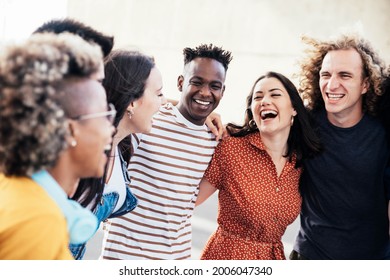 Young happy people laughing together - Multiracial friends group having fun on city street - Diverse culture students portrait celebrating outside - Friendship, community, youth, university concept - Powered by Shutterstock