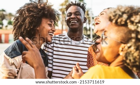 Young happy people laughing together - Multiracial friends group having fun on city street - Diverse culture students portrait celebrating outside - Friendship, community, youth, university concept.	