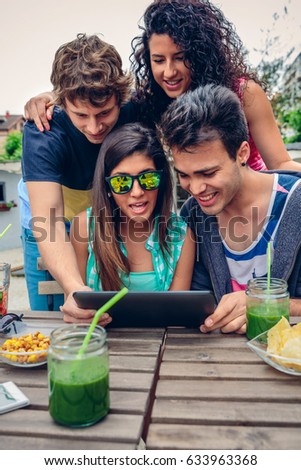 Young happy people looking tablet over table