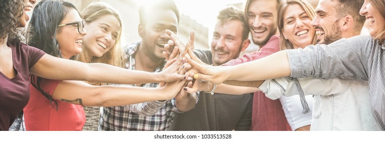 Young happy people stacking hands outdoor - Diverse culture students celebrating together - Youth lifestyle, university, relationship, human resorces, work and friendship concept - Focus on hands - Shutterstock ID 1033513528