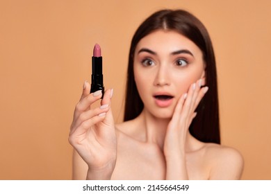 young happy positive woman holding pink lipstick