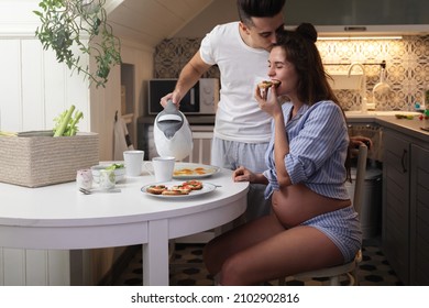 Young and happy pregnant couple eating breakfast in cozy kitchen - Powered by Shutterstock