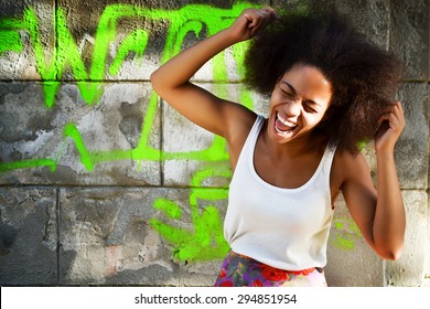 young happy and  pretty afro woman laughing and screaming near old building