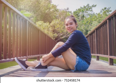 Young happy pretty asian woman sitting on the wood walkway