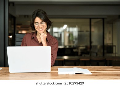 Young happy professional business woman executive working on computer technology in office, busy smiling businesswoman entrepreneur or hr manager using laptop sitting at work desk. Copy space for ads.