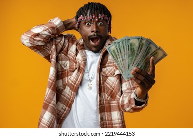 Young Happy Rich African Man In Casual Shirt Holding Dollar Bills Against Yellow Background