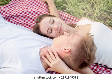 Young Happy Romantic Couple Cuddling On A Picnic Blanket Looking To Each Other