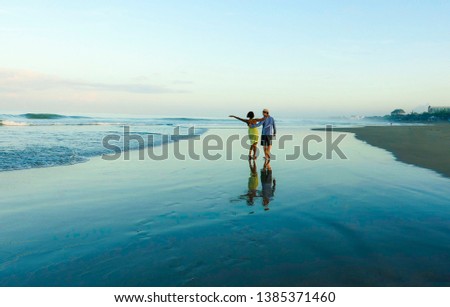 young happy and romantic mixed race couple with attractive black afro American woman ethnicity and white man walking on beach enjoying holidays honeymoon trip together in multiracial love 