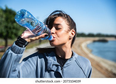 Young happy self loved business fitness runner woman standing and taking a break by drink bottle of water after hard running and jogging exercise for healthy life and clear mind preparing for marathon