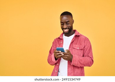 Young happy smiling African American Black hipster man user customer with cellphone in hands standing isolated on yellow background holding smartphone using mobile cell phone scrolling social media. - Powered by Shutterstock