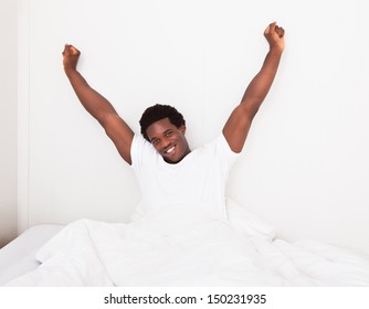 Young Happy Smiling African Man Waking Up At Bedroom