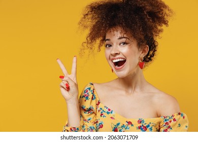 Young happy smiling beautiful friendly fun caucasian woman 20s with culry hair in casual clothes showing victory sign isolated on plain yellow background studio portrait People beauty style concept