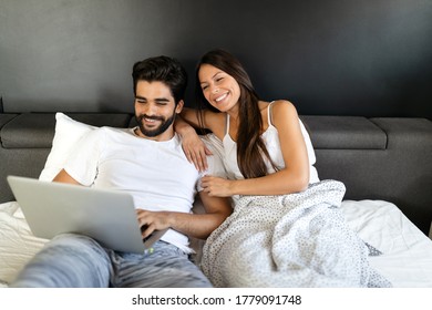 Young happy smiling couple with notebook at bedroom