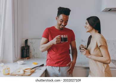 Young Happy Smiling Couple Two Woman American African Man 20s In Casual Clothes Drink Coffe Talk In Morning Have Breakfast Cook Food In Light Kitchen At Home Together Healthy Diet Lifestyle Concept