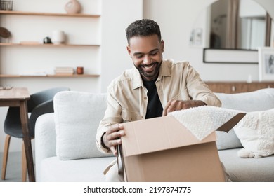 Young Happy Smiling Man Opening Parcel. Delivery, Shipping, Order Online, Home Shopping, Satisfied Customer Concept. 