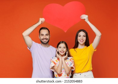 Young Happy Smiling Parents Mom Dad With Child Kid Daughter Teen Girl Wear Basic T-shirts Hold Big Red Heart Above Head Isolated On Yellow Background Studio. Family Day Parenthood Childhood Concept.