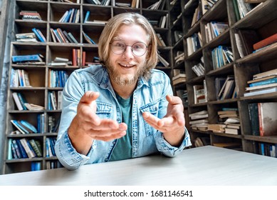 Young happy smiling student man hipster blogger vlogger glasses have online interview skype call shoot self presentation video log explain tell story chat look at camera home library point at camera. - Shutterstock ID 1681146541