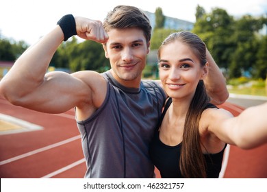 Young Happy Sports Couple Making Selfie Photo On Stadium, Man Showing Biceps