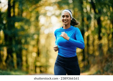 Young happy sportswoman with earbuds running in the park. Copy space. - Powered by Shutterstock