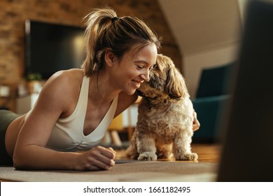 Young Happy Sportswoman Having Fun While Her Dog After Workout At Home. 