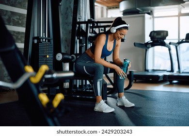 Young happy sportswoman having water break while exercising in a gym. Copy space. - Powered by Shutterstock