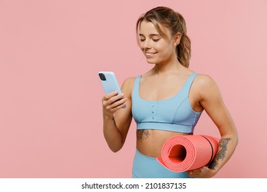 Young Happy Strong Sporty Athletic Fitness Trainer Instructor Woman Wear Blue Tracksuit Spend Time In Home Gym Hold Use Mobile Cell Phone Isolated On Pastel Plain Pink Background Workout Sport Concept