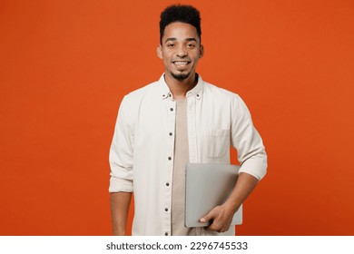 Young happy student IT man of African American ethnicity wears light shirt casual clothes hold cloed laptop pc computer chatting isolated on orange red background studio portrait. Lifestyle concept - Powered by Shutterstock