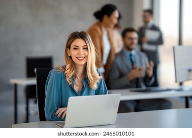 Young happy successful business woman working with laptop in corporate office