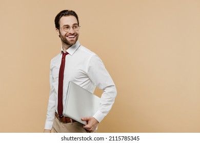 Young happy successful employee business man corporate lawyer 20s in white shirt red tie glasses work in office hold use laptop pc computer look aside on workspace isolated on plain beige background - Shutterstock ID 2115785345