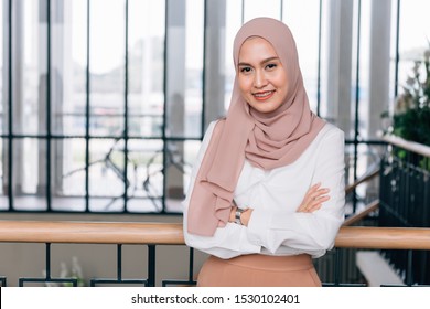 Young Happy And Successful South East Asian Islamic Business Woman With Arms Crossed In Business Corporate Building Setting Looks At Camera
