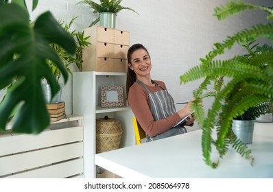 Young Happy Successful Woman Florist In Her Flowershop Surrounded With Flowers In Flowerpots Working Job She Love As Small Business Owner.