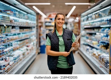 Young happy supermarket manager standing at produce aisle and looking at camera. - Powered by Shutterstock