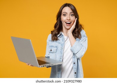 Young happy surprised shocked brunette fun woman 20s wearing stylish casual denim shirt white t-shirt hold laptop pc computer hold face look camera isolated on yellow color background studio portrait. - Powered by Shutterstock