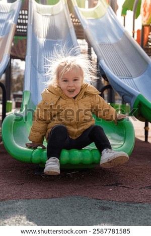 Similar – Image, Stock Photo Child laughing joyfully while making a snow angel, dressed in a vibrant winter coat and hat