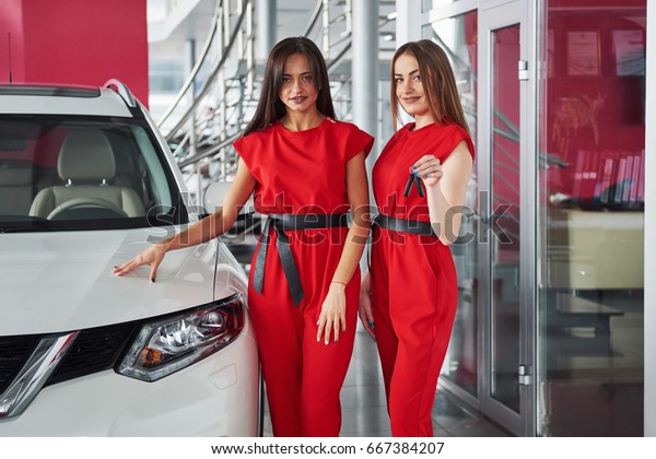 Young happy two woman near the car with keys in hand\
- concept of buying car.