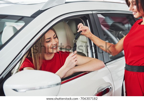Young happy two woman near the car with keys in hand\
- concept of buying car.