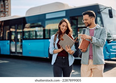 Young happy university students going through lecture notes while arriving at bus station. - Powered by Shutterstock