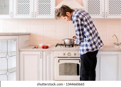 Young Happy Unmarried Single Man Bachelor Cooking At The Kitchen 