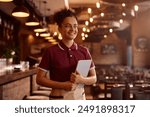 Young happy waitress using digital tablet while working in a bar. Copy space. 