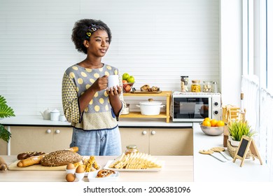 Young happy woman african american afro hair drinking coffee on the kitchen in the morning. - Powered by Shutterstock