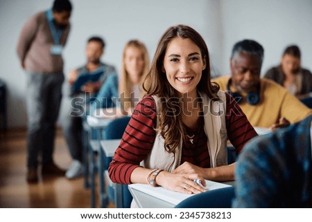 Young happy woman attending adult education training class in lecture hall and looking at camera. 