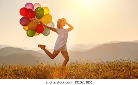 young happy woman with balloons at sunset in summer